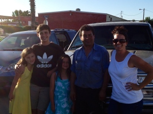 A grateful family poses with a generous man in front of the car he loaned us and the one he repaired.