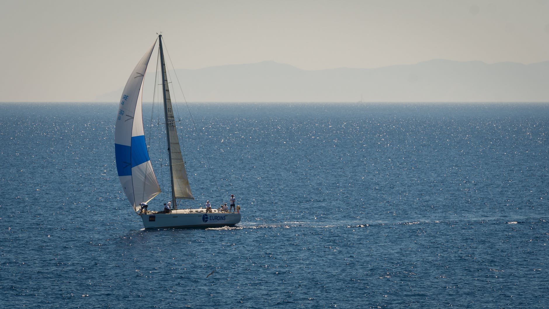 white and blue sailboat on sea